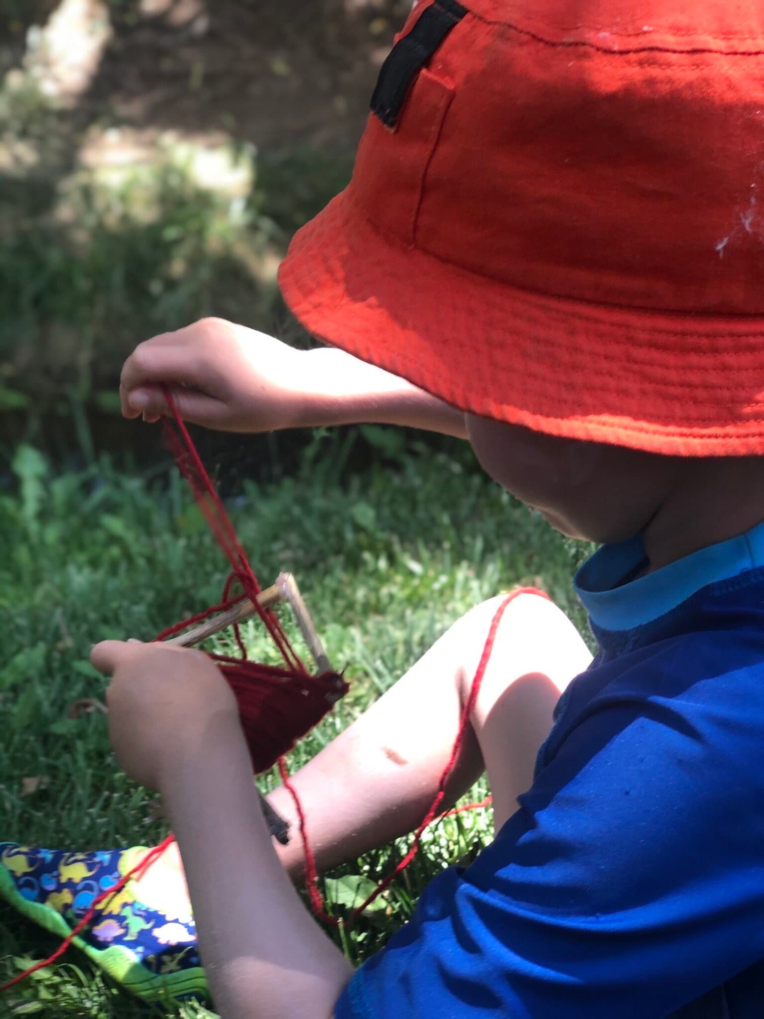 Small hands weaving yarn on a simple wooden loom