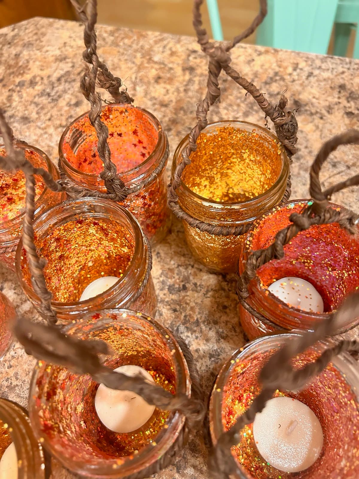 Handmade jar lanterns in orange and gold glitter, each with a small candle inside